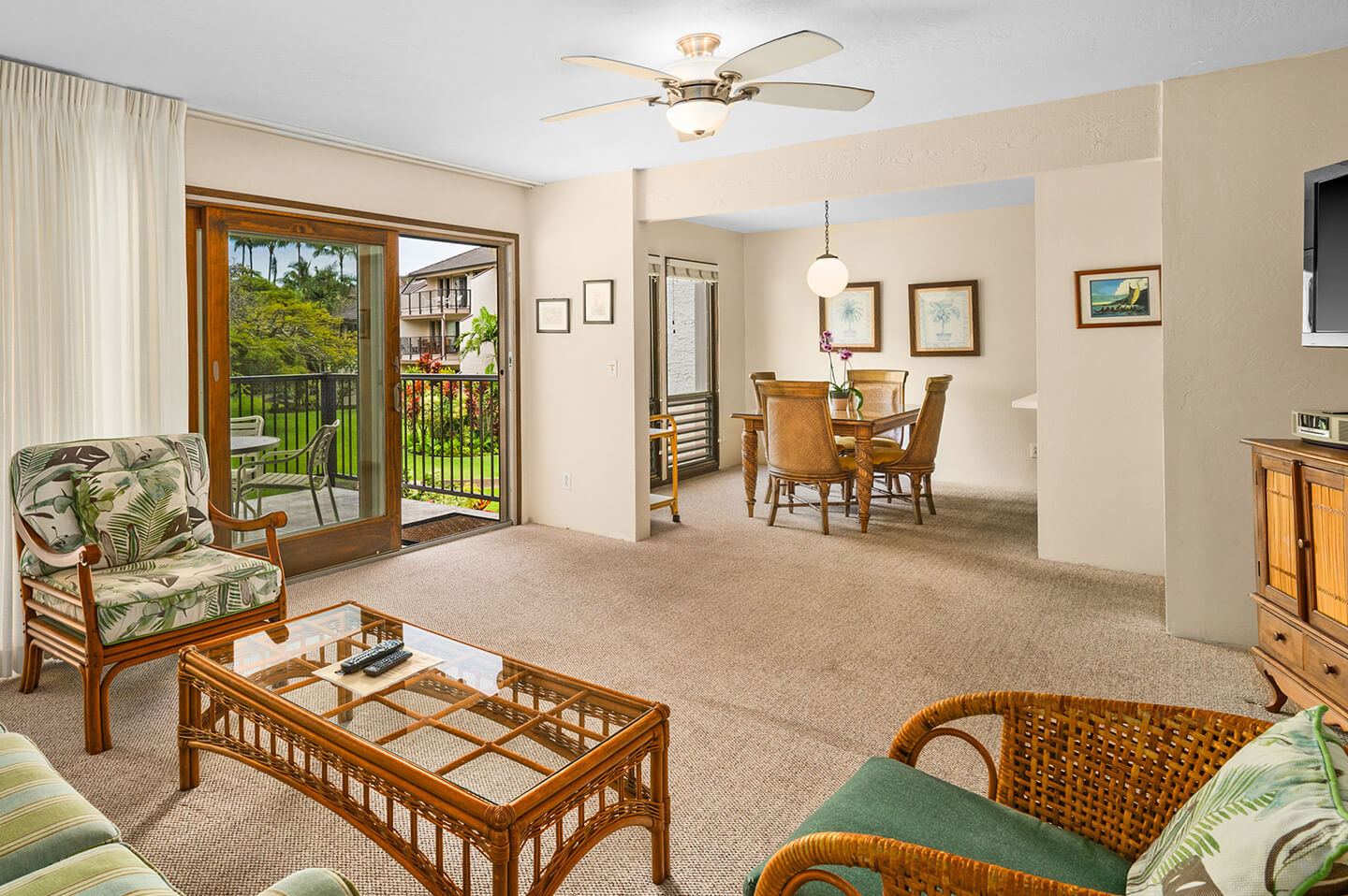 Living room with seating, coffee table, TV, balcony, dining area.