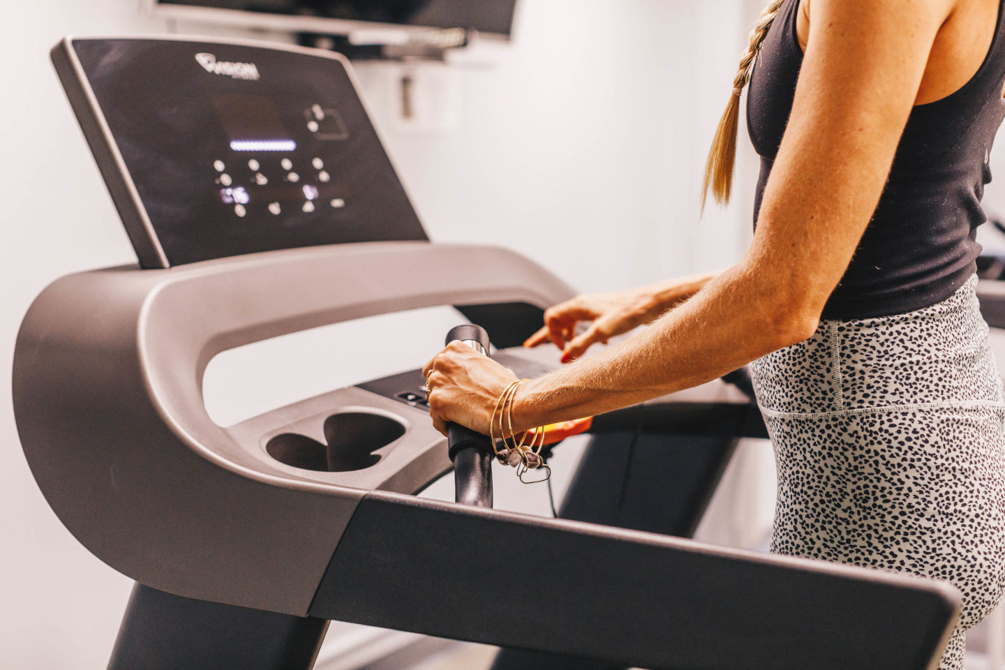 Lady on a treadmill at the Aston Waikiki Sunset fitness center setting up her machine for a workout.