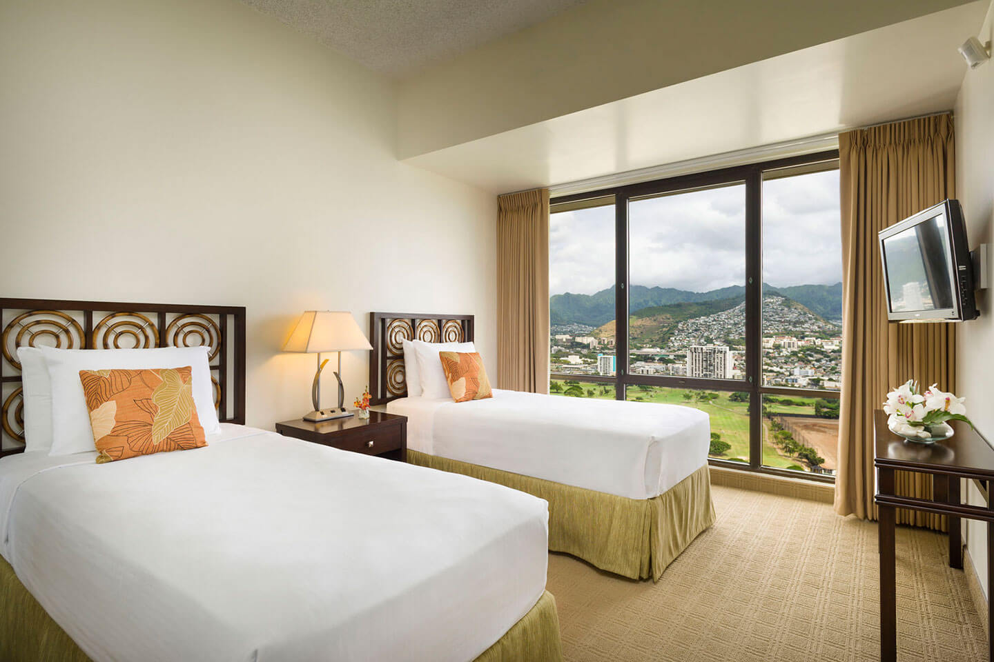 Room with 2 beds, TV, and large picture window with mountain view.