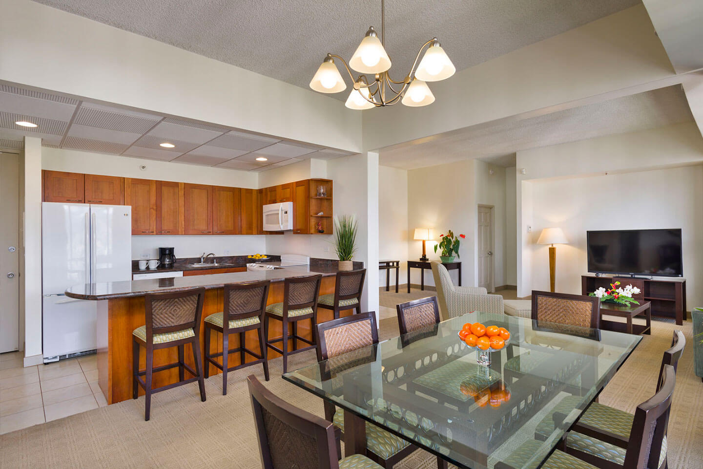 Kitchen with a refrigerator and countertop seating, and dining area with glass top table and chairs.