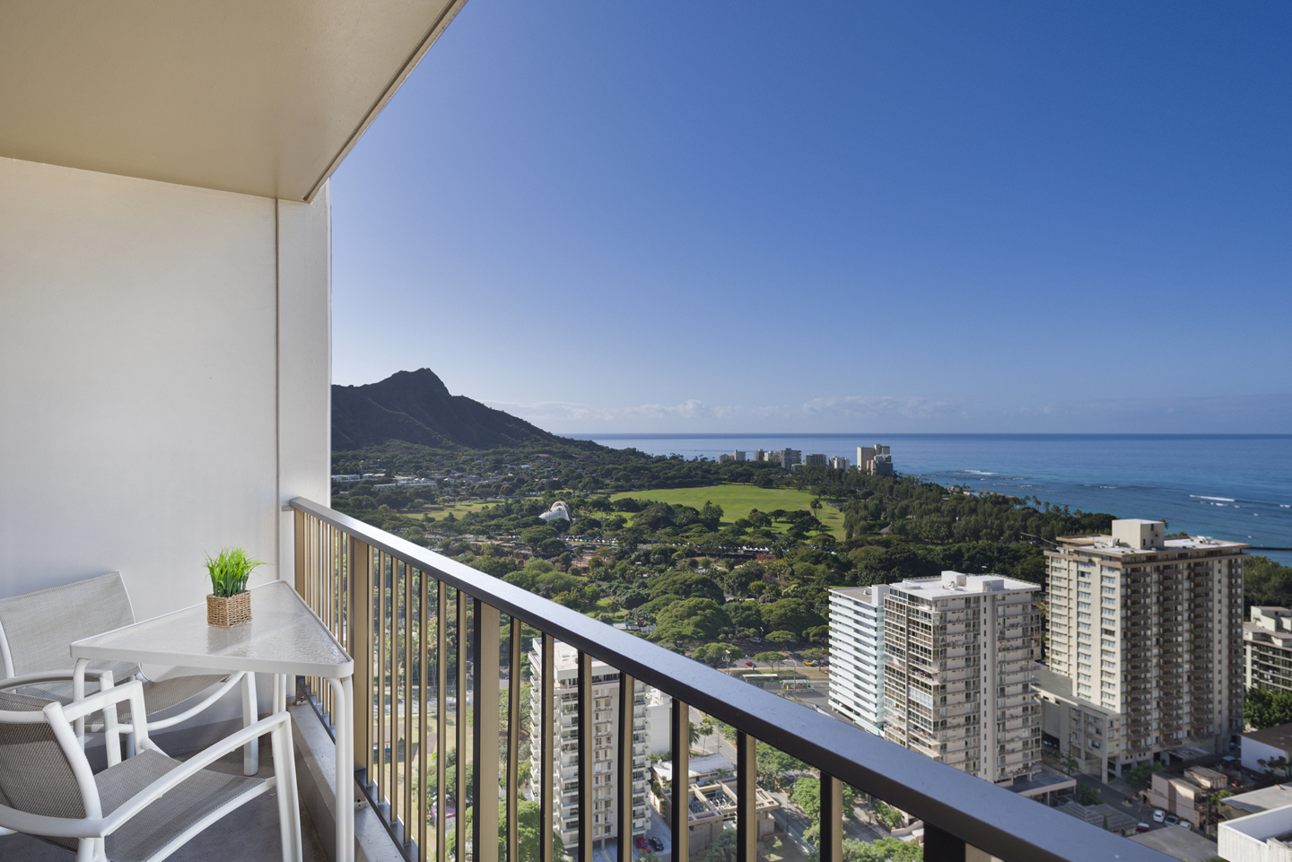 Balcony with chairs and table, views of Diamond Head and ocean.
