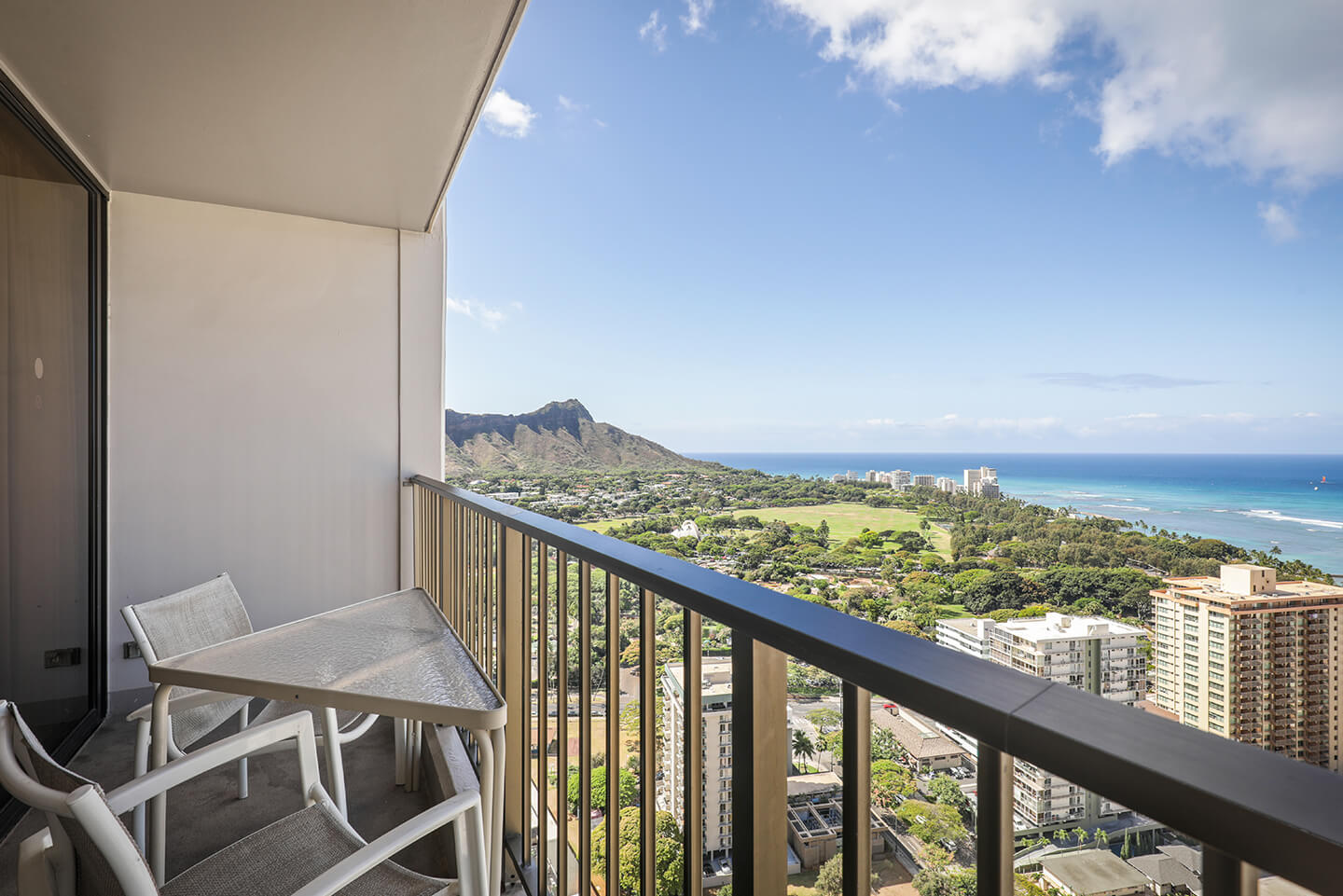 Balcony with chairs and table, views of Diamond Head and ocean.