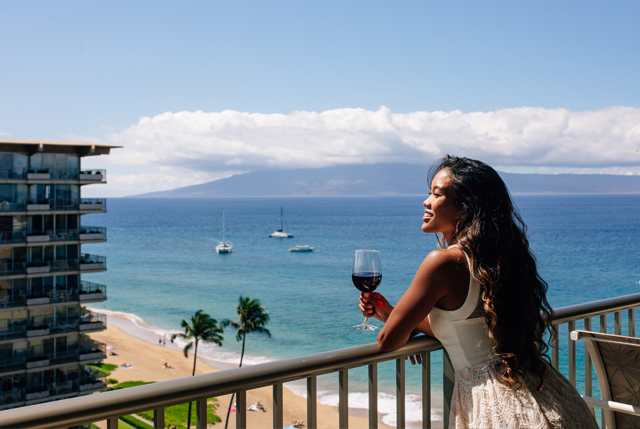 Female enjoying a glass of wine on a balcony while watching the beach and ocean..