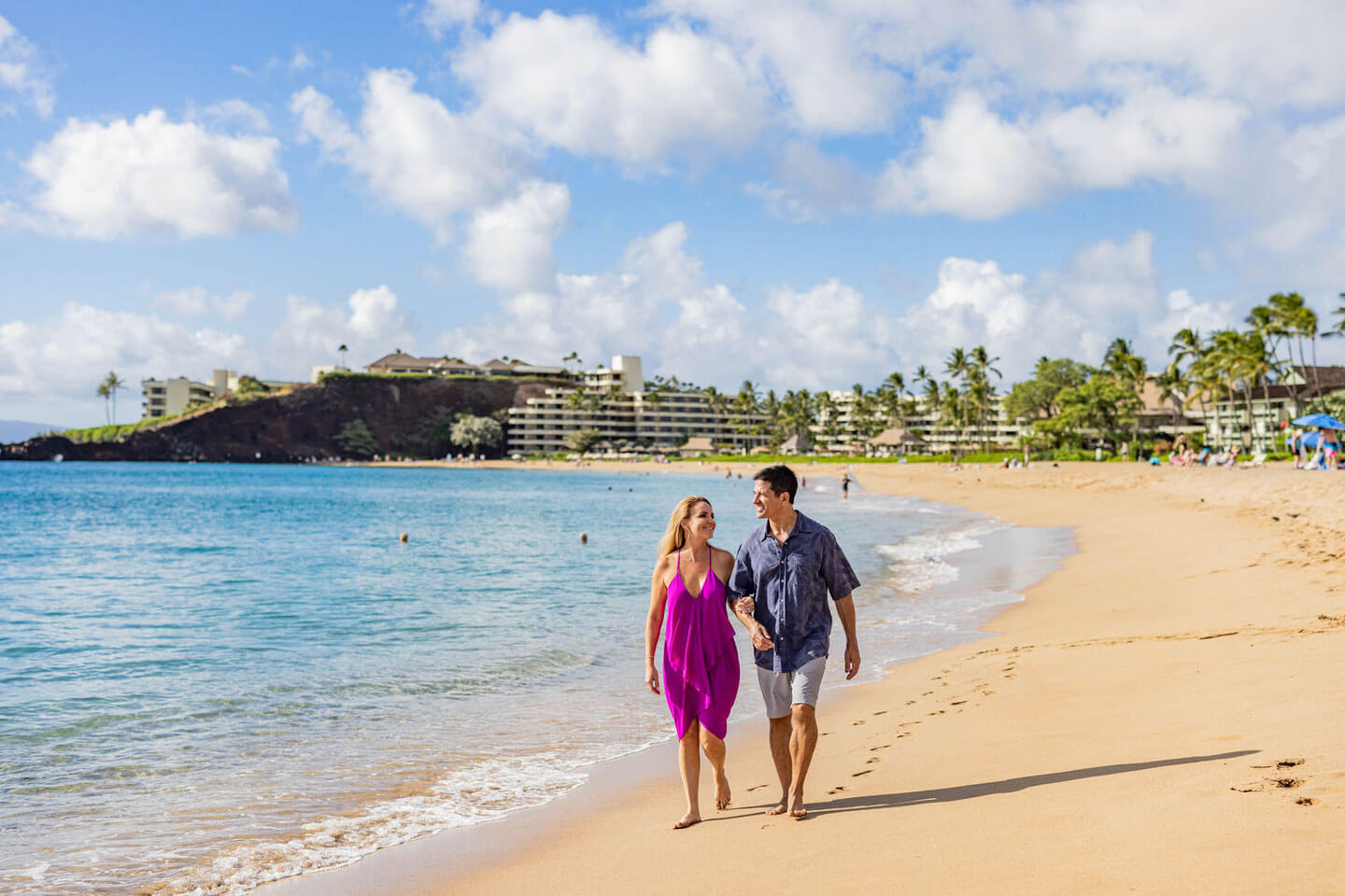 Couple walking along sandy beachfront.