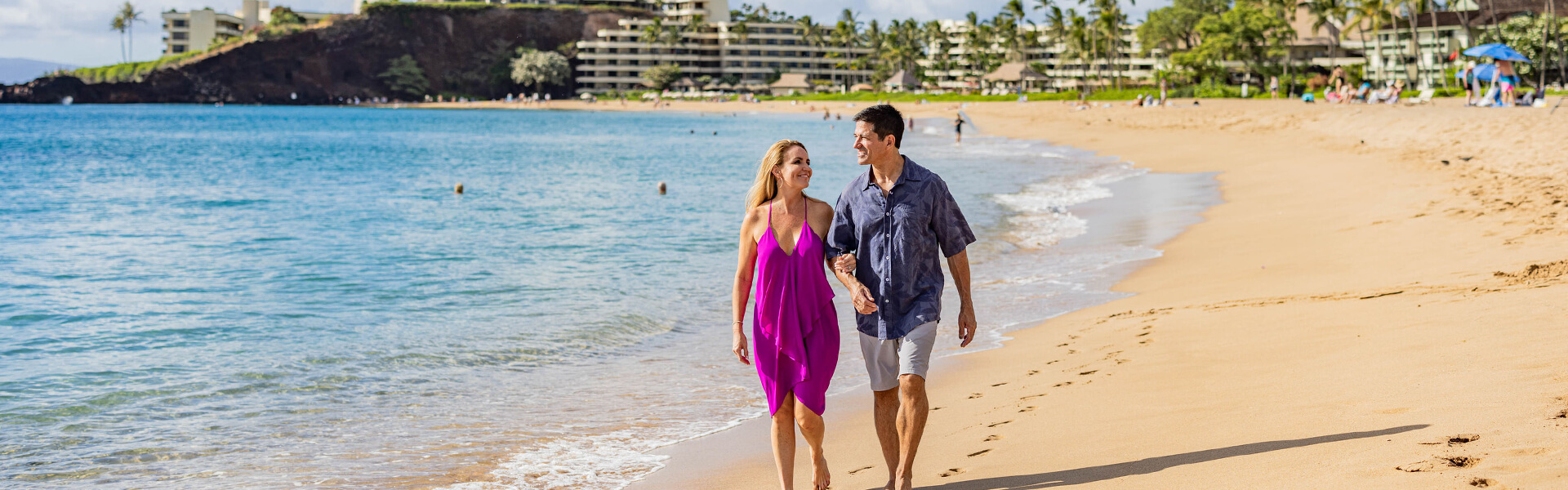 Couple walking along breachfront.