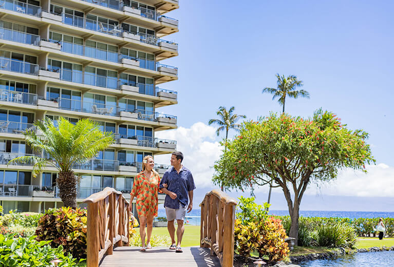 Couple walking on a bridge in resort garden.