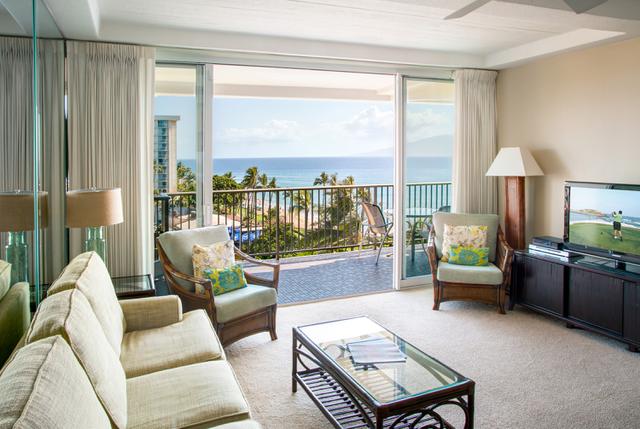 Living room with couch, coffee table, lapms, TV, balcony