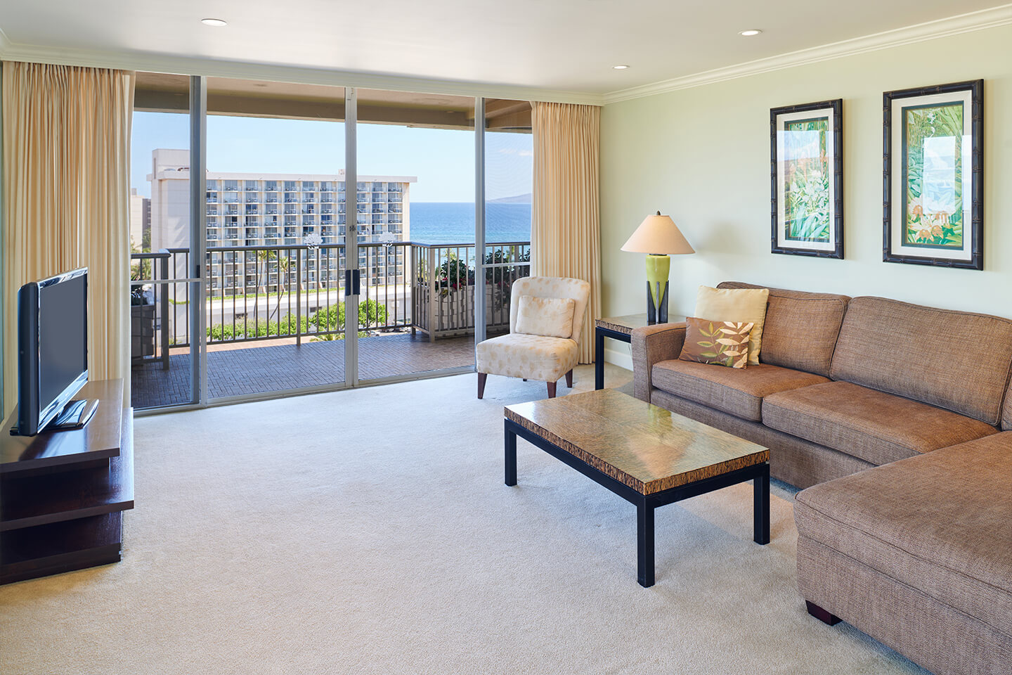 Living area with a couch, coffee table, TV, and balcony.