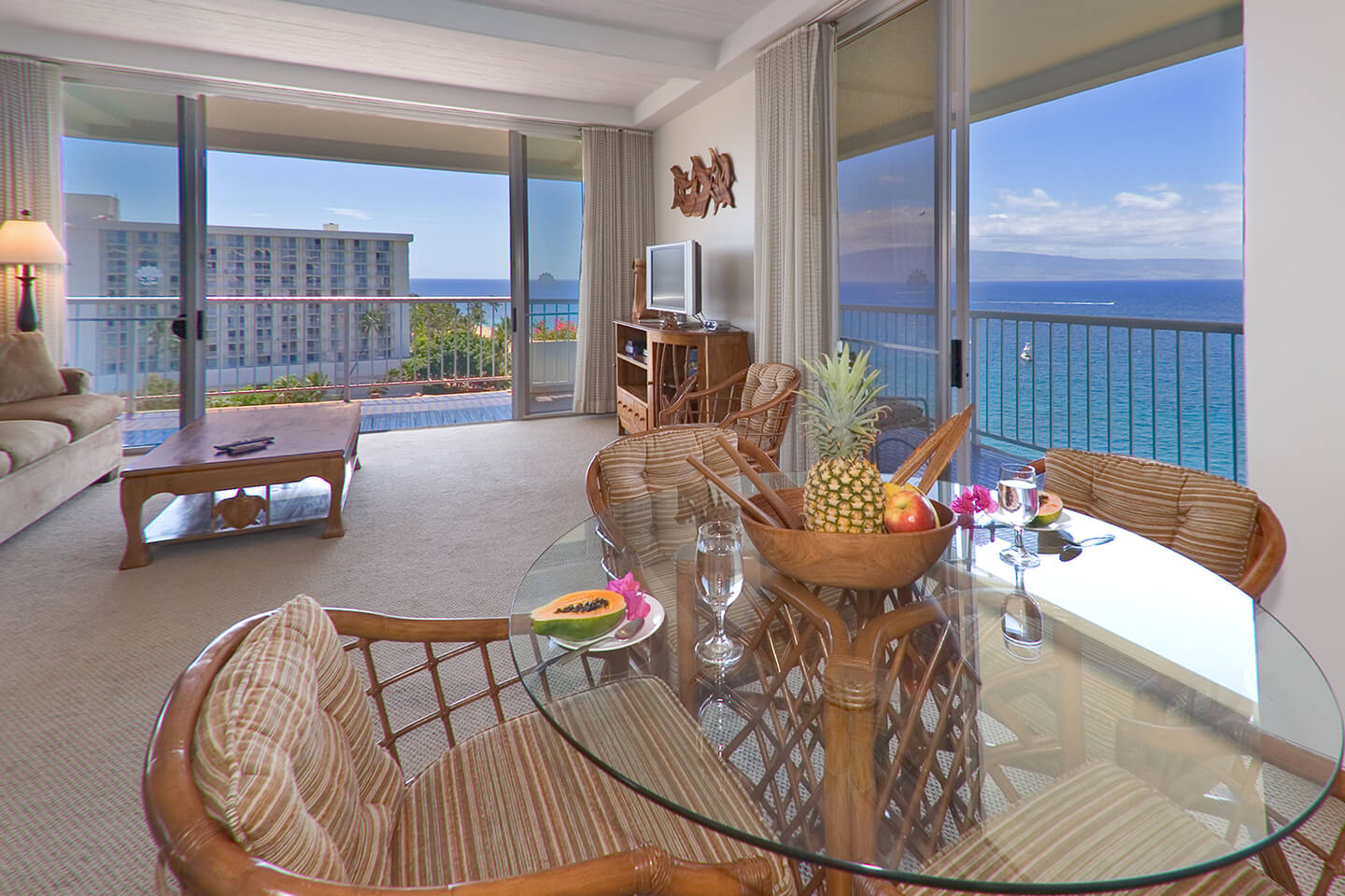 Living area with dining table, chairs, large picture window and balcony with ocean views.