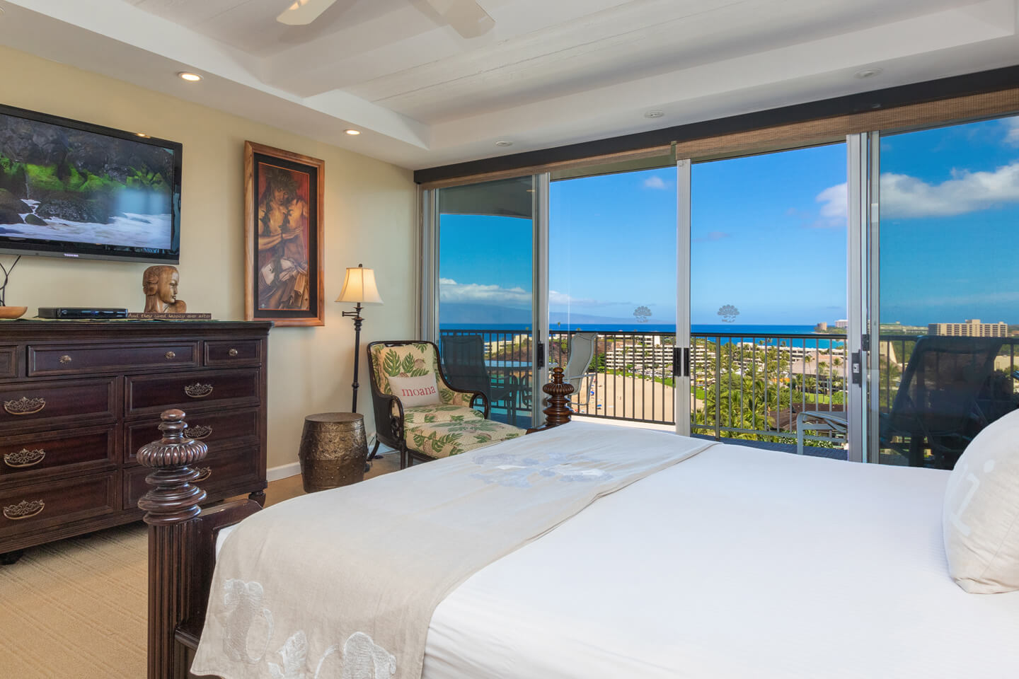 Room with a bed, TV, dresser, balcony with ocean view.