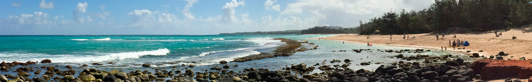 Baldwin beach shore line with crystal blue waves breaking over black rocks and people on the beach